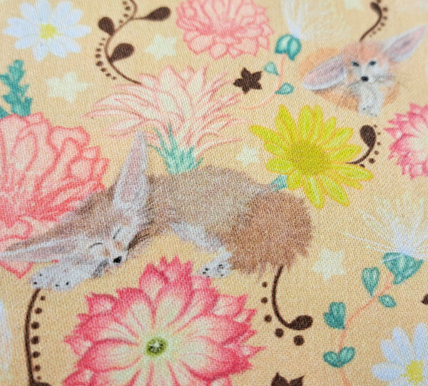 Gros plan sur le motif “Murmures du désert” imprimé sur popeline : fennec endormi et fleurs du désert dans des tons sable et pastel.